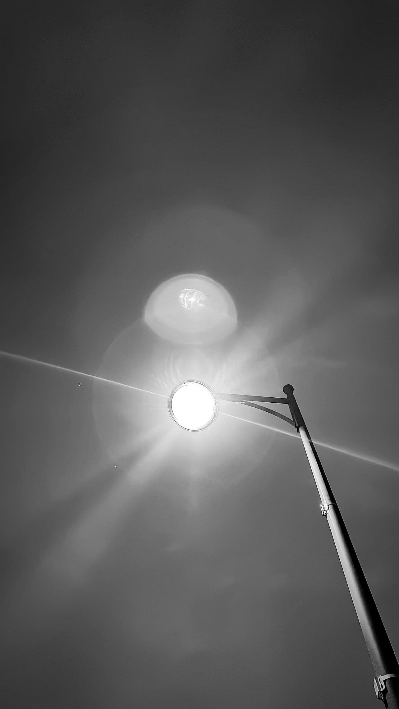 Lampadaire en noir et blanc à contre-jour, flare lumineux