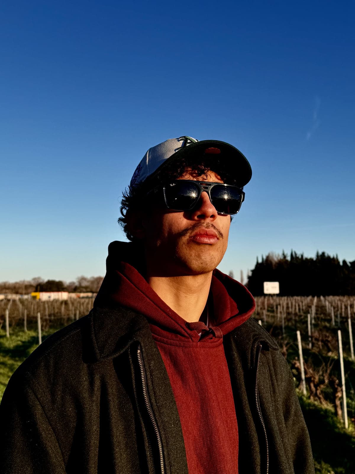 Ryan Delouvroy de face, casquette et lunettes noires, ciel bleu